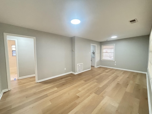 empty room with baseboards, light wood finished floors, and visible vents