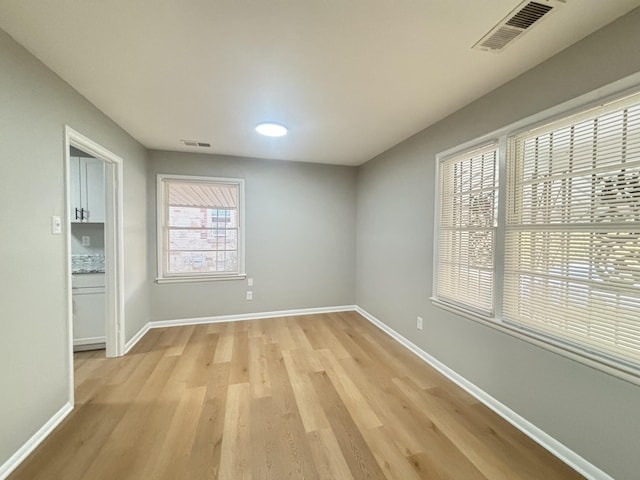 unfurnished room with light wood-style floors, baseboards, and visible vents