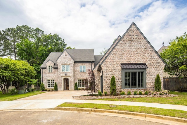 french country style house with concrete driveway, brick siding, and fence