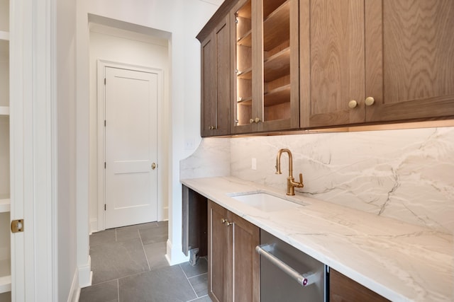 bar featuring a sink, decorative backsplash, dishwasher, and dark tile patterned flooring
