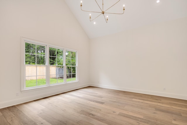 empty room with an inviting chandelier, high vaulted ceiling, recessed lighting, baseboards, and light wood-type flooring