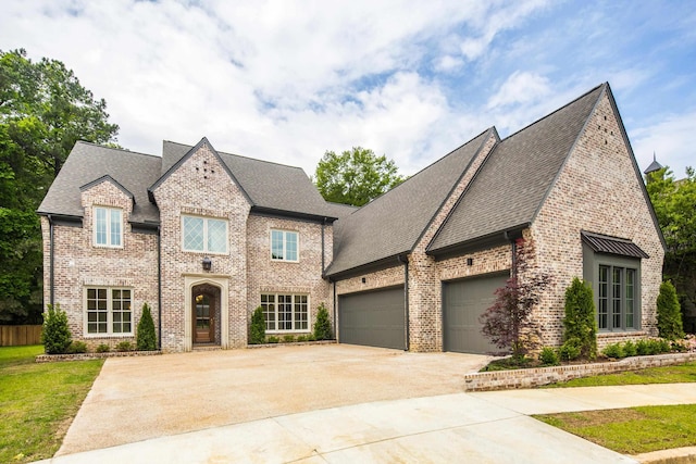 french provincial home featuring brick siding, driveway, roof with shingles, and a garage