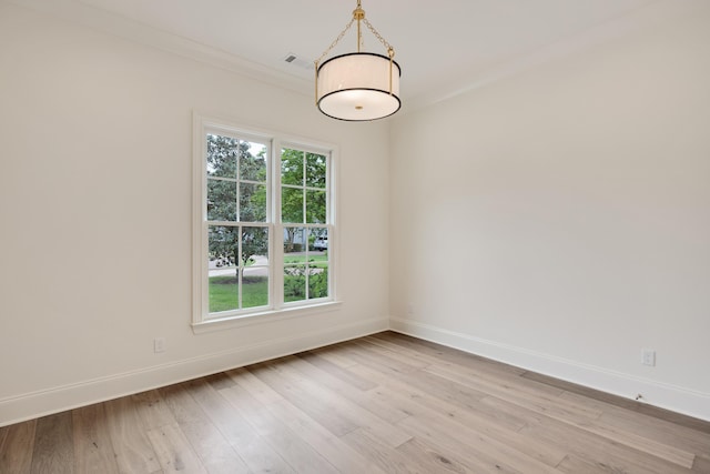 spare room featuring baseboards, ornamental molding, and light wood-style flooring