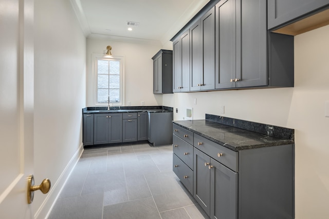 washroom with visible vents, baseboards, a sink, cabinet space, and light tile patterned floors