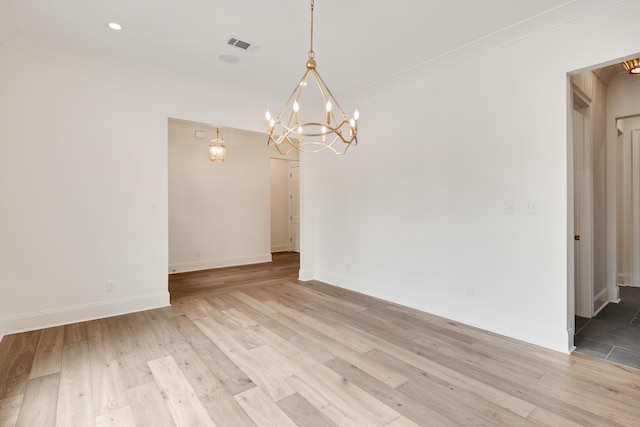 spare room featuring baseboards, a notable chandelier, ornamental molding, and visible vents
