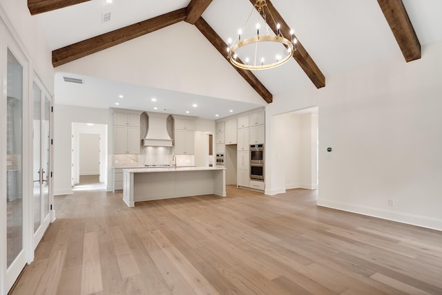 unfurnished living room with visible vents, beam ceiling, high vaulted ceiling, a chandelier, and french doors