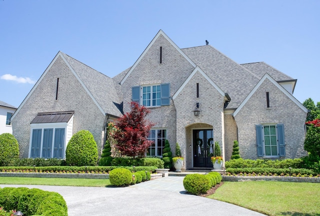 view of front of property with brick siding, roof with shingles, and a front lawn