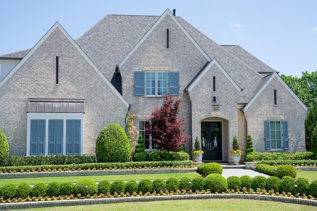 view of front of house with a shingled roof and brick siding