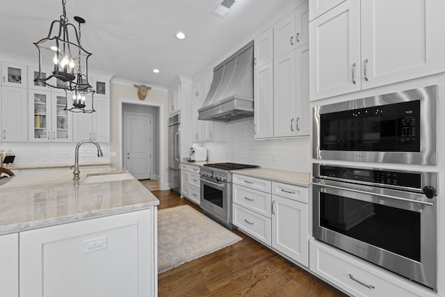 kitchen featuring built in appliances, custom exhaust hood, a sink, backsplash, and ornamental molding