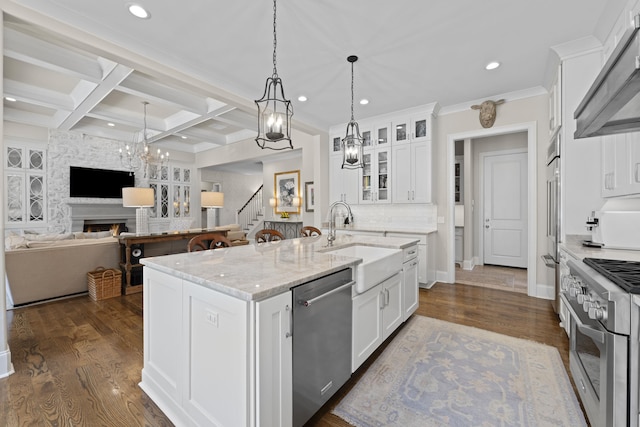kitchen with high quality appliances, a sink, under cabinet range hood, a chandelier, and a large fireplace