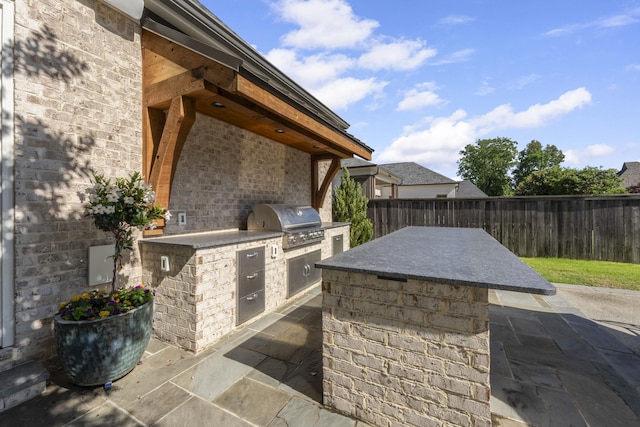 view of patio featuring exterior kitchen, grilling area, and a fenced backyard