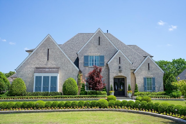 view of front of property with brick siding, french doors, and a shingled roof