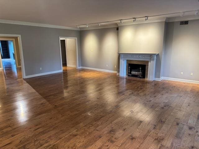 unfurnished living room featuring crown molding, track lighting, baseboards, and visible vents