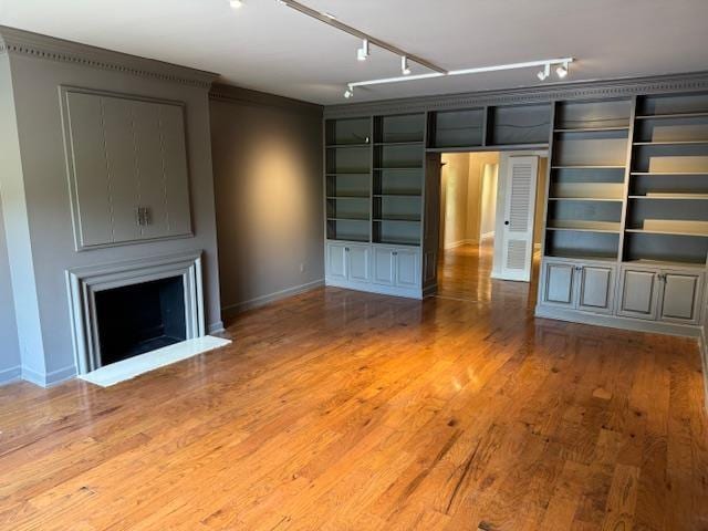 unfurnished living room featuring track lighting, baseboards, a large fireplace, and wood finished floors