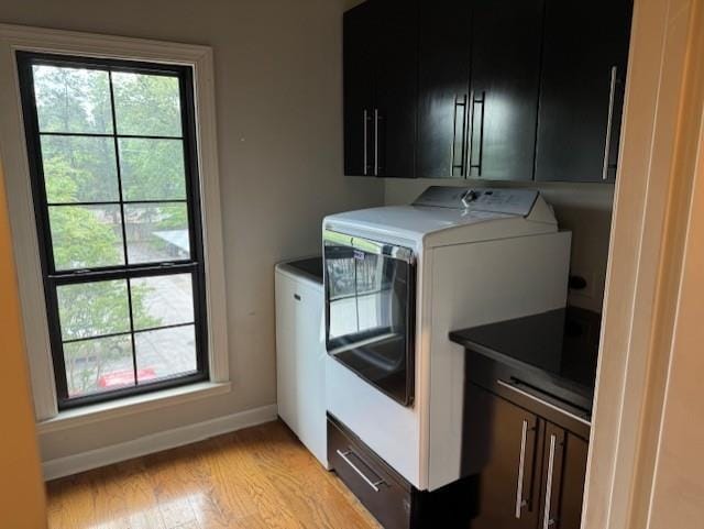 clothes washing area with baseboards, light wood-style flooring, and cabinet space