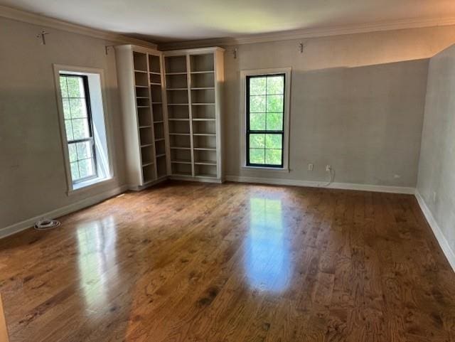 spare room featuring crown molding, baseboards, and wood finished floors