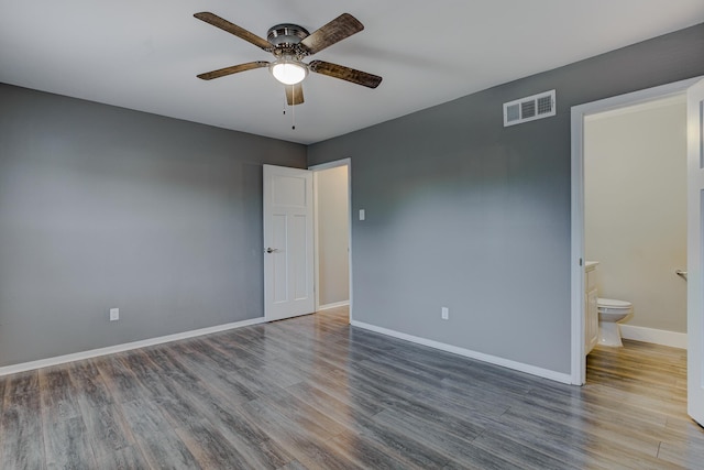 unfurnished bedroom with connected bathroom, baseboards, visible vents, and wood finished floors