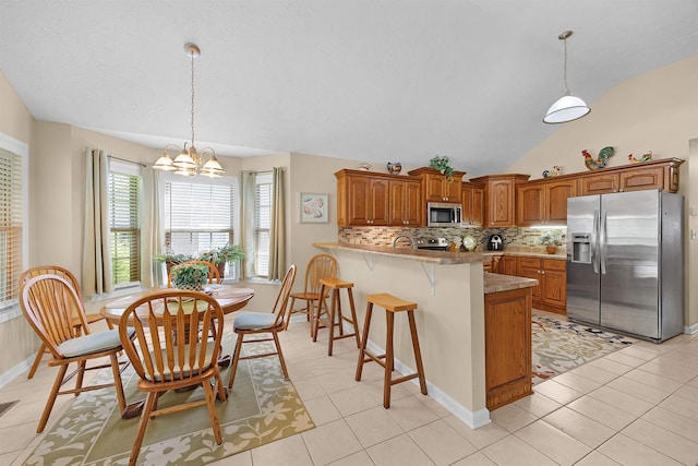 165 Ping Hill Dr, Counce, TN 38326 - kitchen featuring brown cabinets, a notable chandelier, appliances with stainless steel finishes, a peninsula, and decorative backsplash