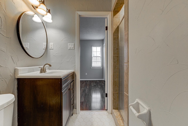 bathroom featuring toilet, a textured ceiling, baseboards, and vanity