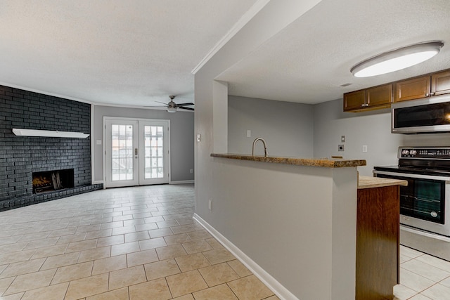 kitchen with light tile patterned floors, ceiling fan, stainless steel appliances, and a textured ceiling