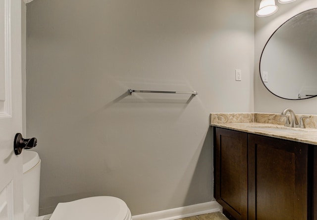 half bath featuring toilet, baseboards, and vanity