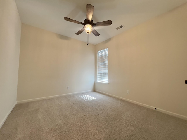 carpeted empty room with baseboards, a ceiling fan, and visible vents