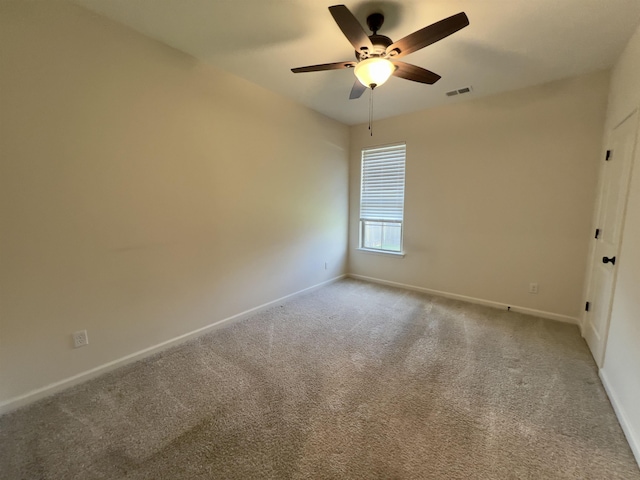 carpeted spare room featuring visible vents, a ceiling fan, and baseboards