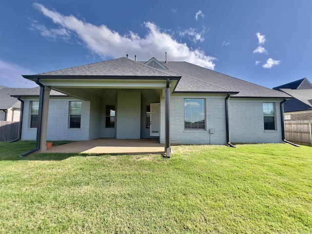 back of house with a patio, a lawn, fence, and brick siding