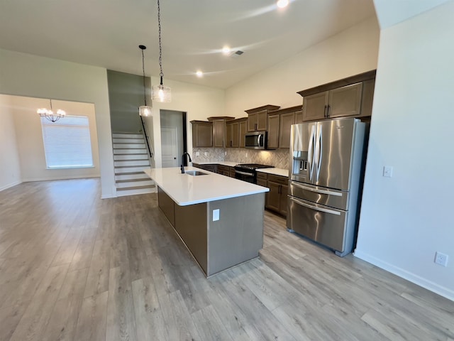 kitchen featuring dark brown cabinets, a notable chandelier, appliances with stainless steel finishes, a sink, and a kitchen island with sink