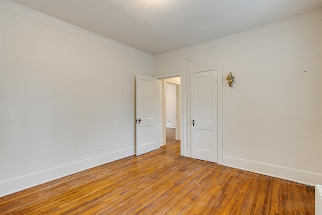 spare room featuring baseboards, ornamental molding, and light wood-style flooring