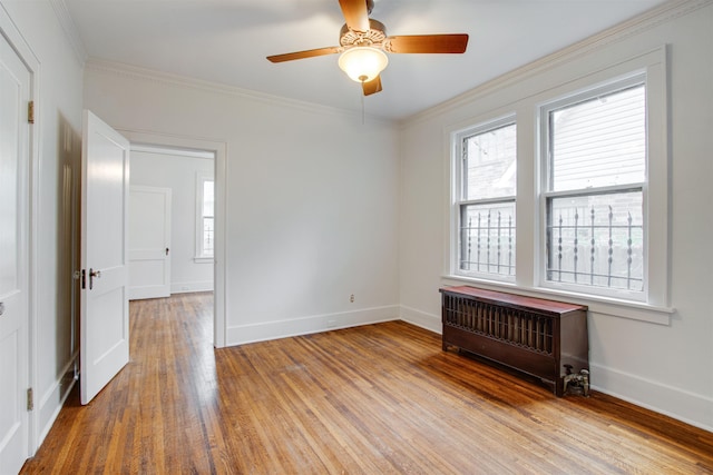 spare room featuring radiator, baseboards, a ceiling fan, and wood finished floors