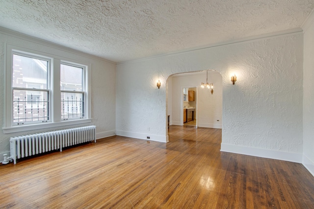 unfurnished room with a textured ceiling, a textured wall, radiator heating unit, and wood finished floors
