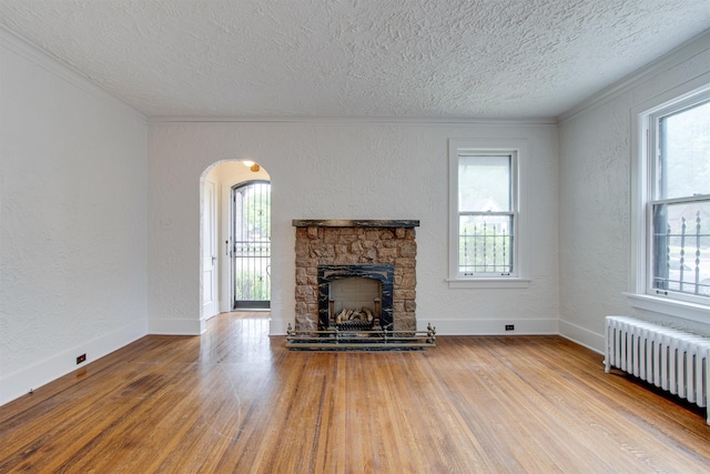 unfurnished living room with plenty of natural light, radiator, a textured wall, and a textured ceiling