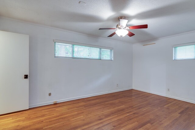 empty room featuring crown molding, ceiling fan, wood finished floors, and a healthy amount of sunlight
