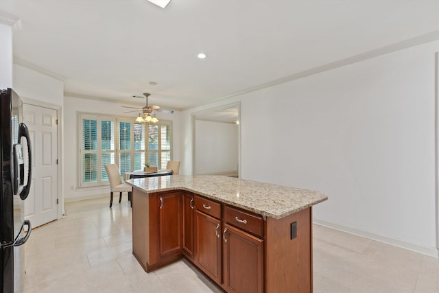 kitchen featuring crown molding, light stone countertops, black refrigerator with ice dispenser, a ceiling fan, and a kitchen island