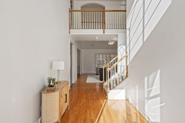 entryway featuring baseboards, a high ceiling, light wood finished floors, and stairs
