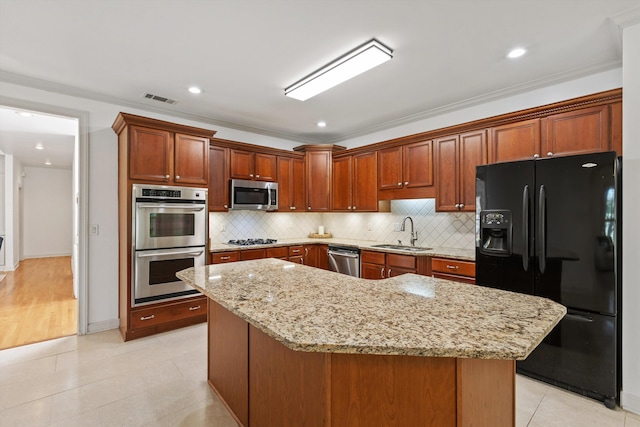 kitchen with visible vents, light stone counters, a sink, backsplash, and stainless steel appliances