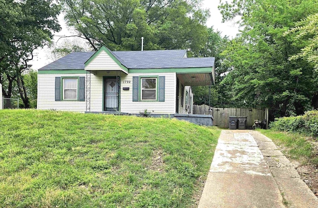 bungalow-style house featuring concrete driveway, fence, a shingled roof, and a front yard