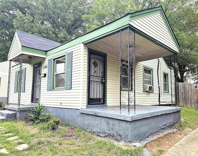 view of front facade featuring fence, cooling unit, and a porch