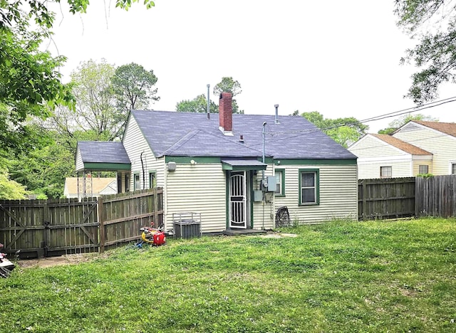 rear view of house featuring a lawn, a chimney, a fenced backyard, and central AC unit