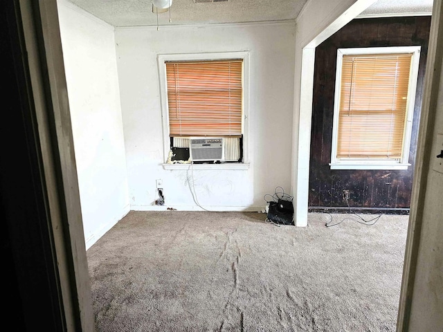 empty room with carpet, a textured ceiling, and cooling unit