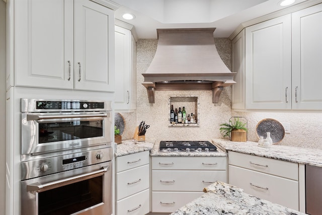 kitchen featuring custom range hood, white cabinetry, tasteful backsplash, and stainless steel appliances