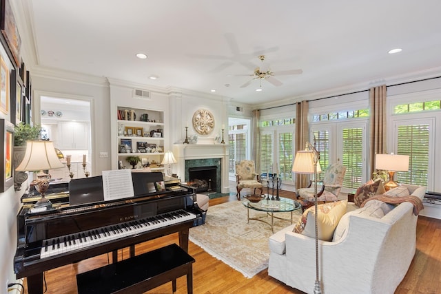 living area with crown molding, a ceiling fan, wood finished floors, and a fireplace