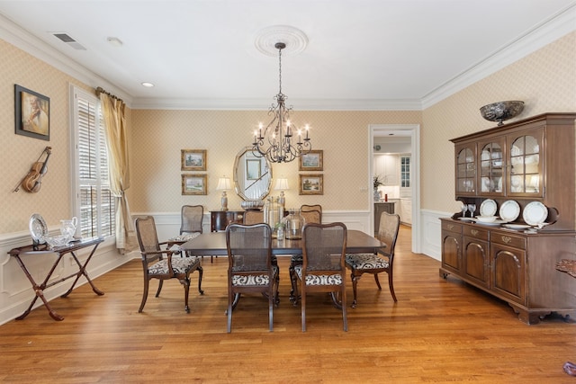 dining area featuring crown molding, a notable chandelier, and wainscoting