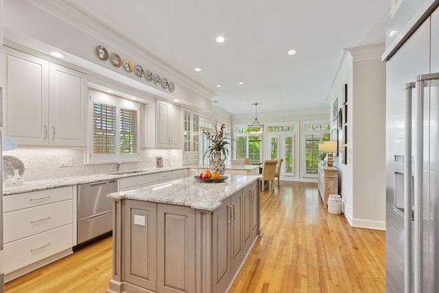 kitchen with crown molding, a kitchen island, dishwasher, light wood-type flooring, and backsplash
