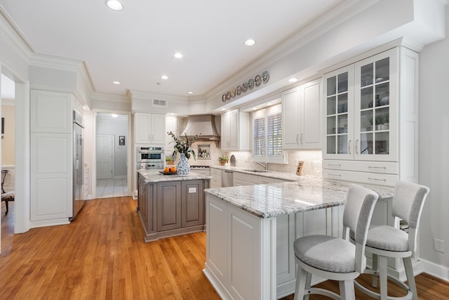 kitchen featuring crown molding, glass insert cabinets, light wood-style floors, white cabinets, and appliances with stainless steel finishes