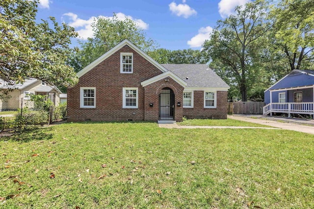 view of front facade featuring crawl space, an outbuilding, brick siding, fence, and a front lawn