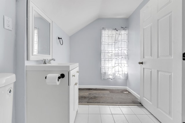 half bath featuring vanity, toilet, tile patterned floors, a healthy amount of sunlight, and lofted ceiling