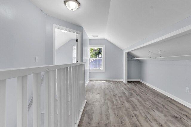 additional living space featuring baseboards, wood finished floors, vaulted ceiling, and visible vents