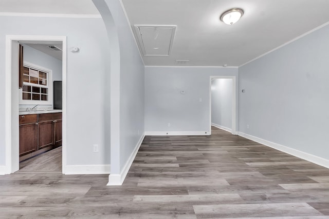 empty room with attic access, visible vents, crown molding, wood finished floors, and baseboards